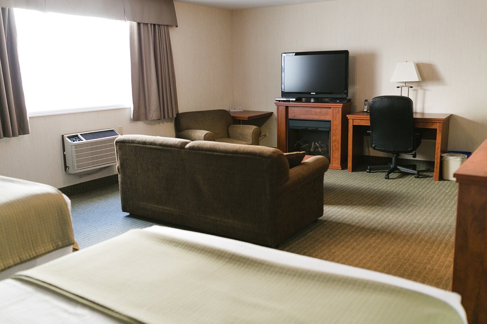 Een hotelkamer met een bank, een televisie, een bureau, een stoel en een bed.