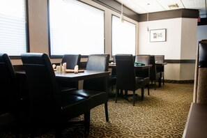 A conference room with tables and chairs, large windows, and a patterned carpet.