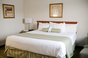 A hotel room with a large bed, a bedside table with a lamp, and two framed pictures on the wall.