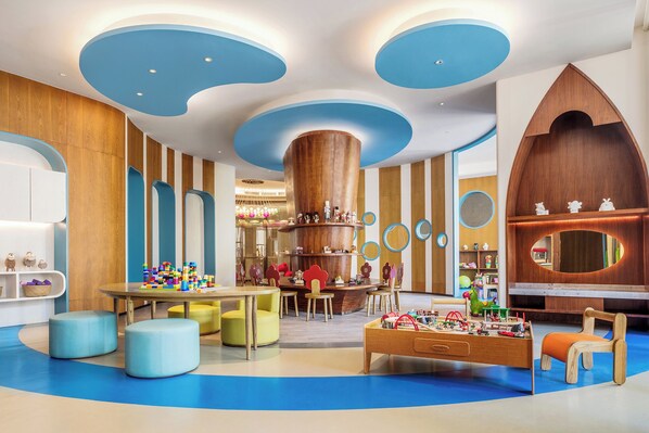 A modern children's play area with colorful toys, a central play table, and a large wooden play structure. - Xiamen Marriott Hotel & Conference Centre (Xiamen)