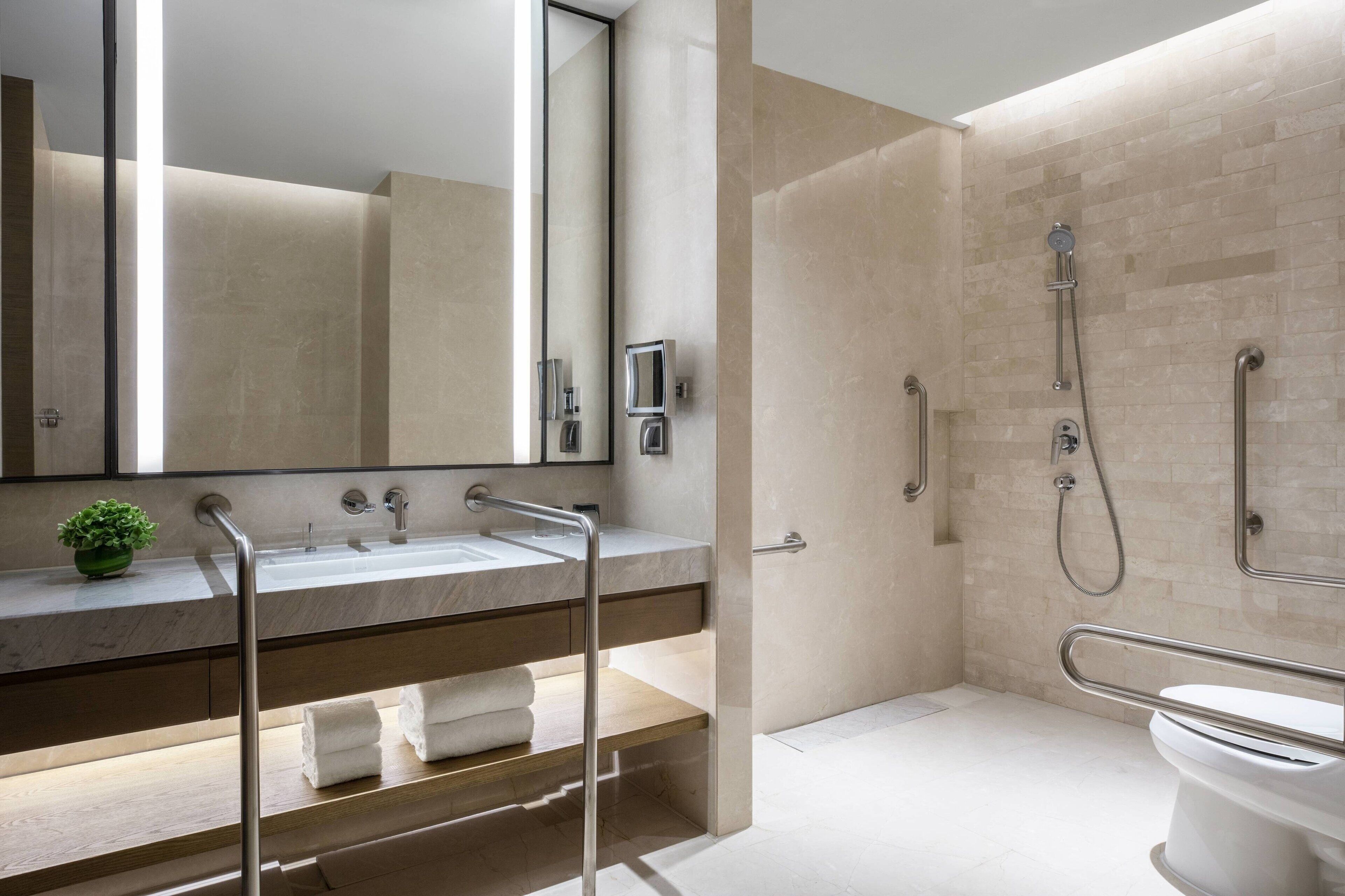 Een moderne badkamer met een grote spiegel, een wastafel, een douche en een toilet.