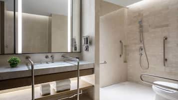 Een moderne badkamer met een grote spiegel, een wastafel, een douche en een toilet.