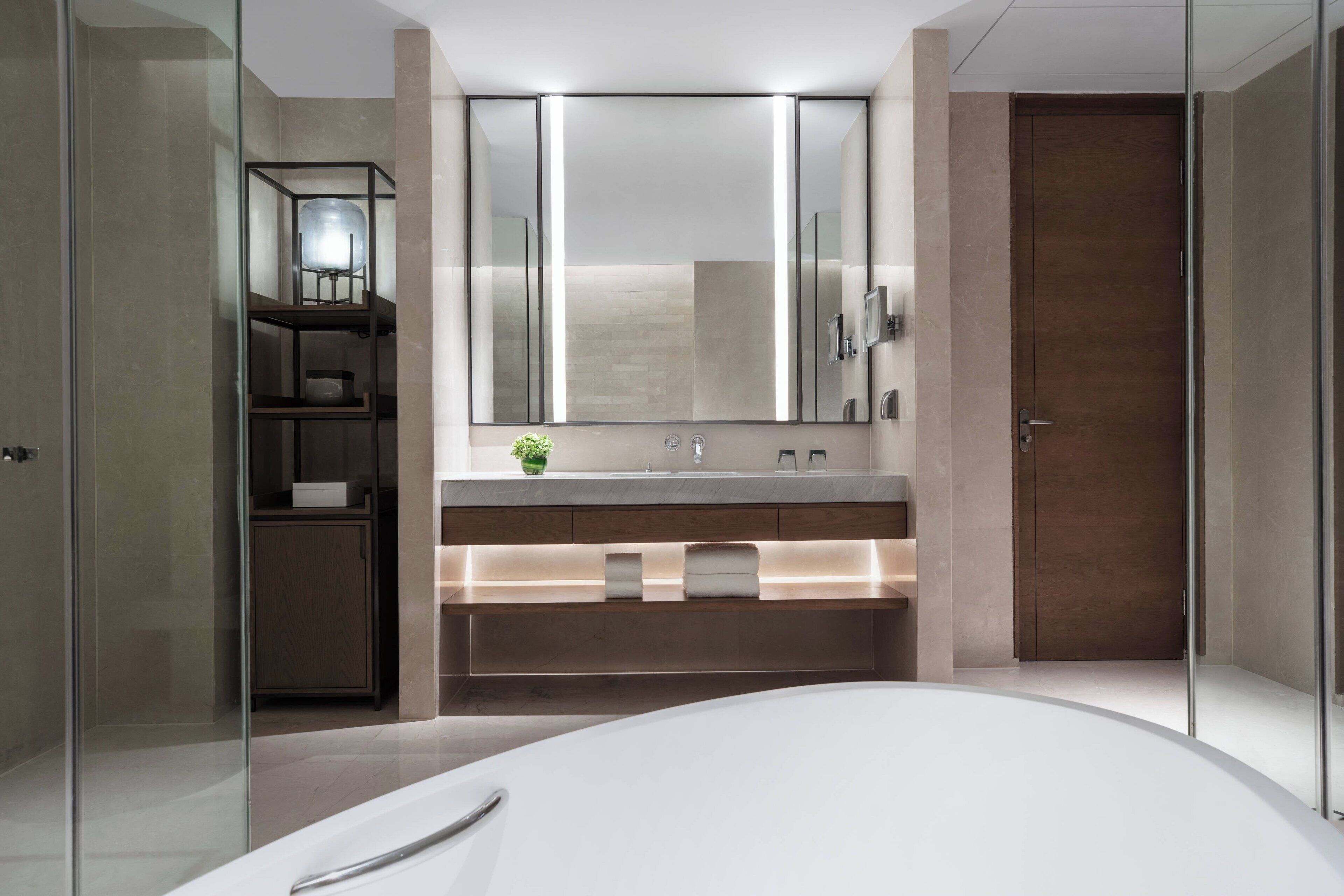 Ein modernes Badezimmer mit einem großen Spiegel, einer weißen Badewanne und einer Duschkabine aus Glas.