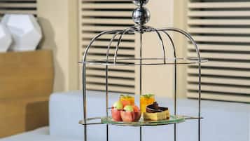 A three-tiered dessert stand with various pastries and a glass of drink on a table.