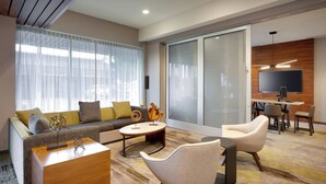 A modern living room with a sofa, armchairs, a coffee table, and a TV. - Courtyard by Marriott Los Angeles LAX/Hawthorne (Hawthorne)