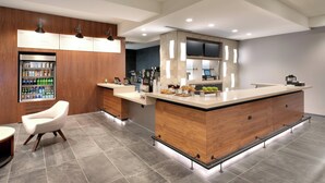 A modern kitchen with a central island, wooden cabinetry, and a built-in refrigerator. - Courtyard by Marriott Los Angeles LAX/Hawthorne (Hawthorne)