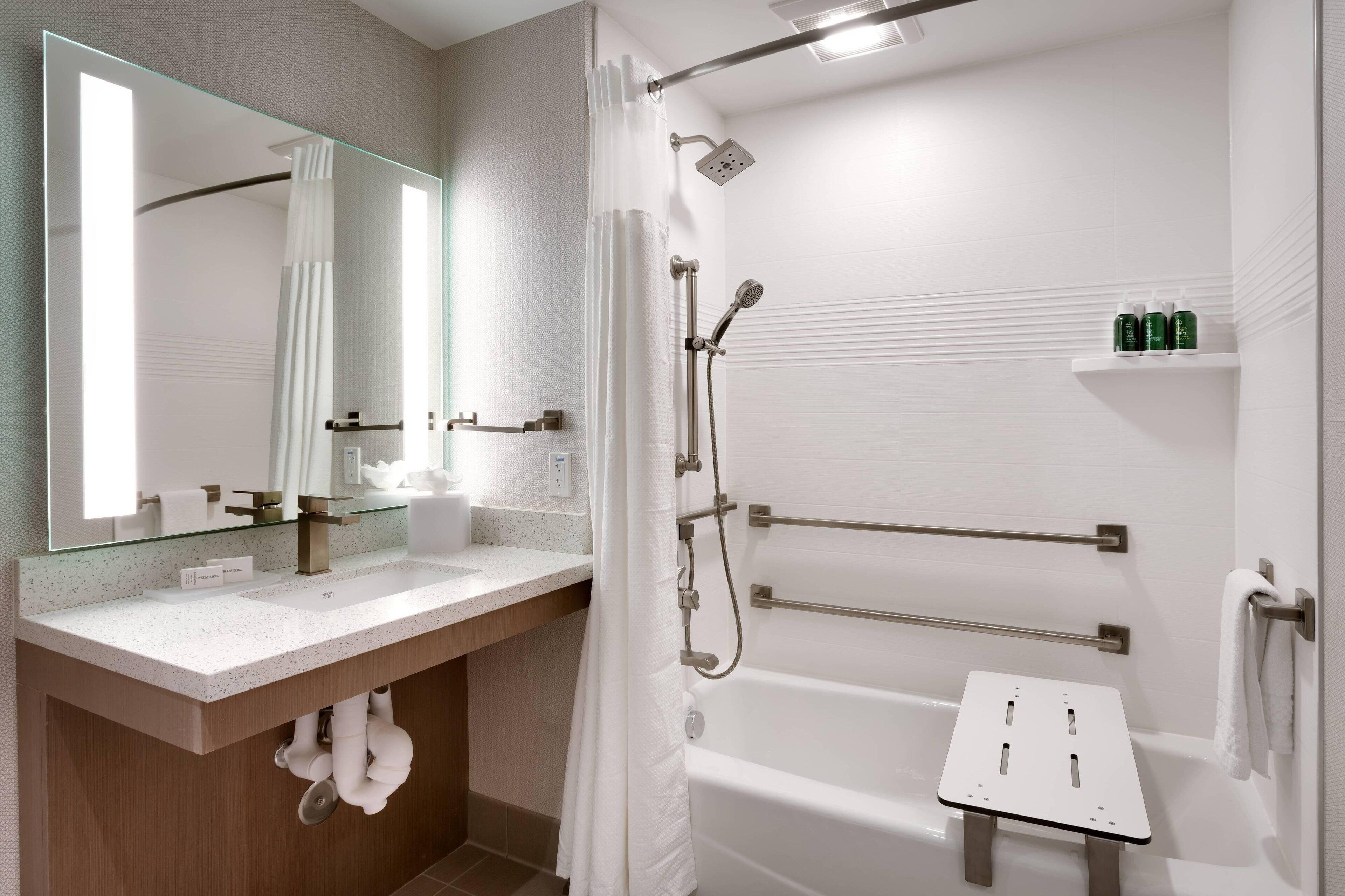 A modern bathroom with a glass shower enclosure, a bathtub, a vanity with a mirror, and a towel rack.