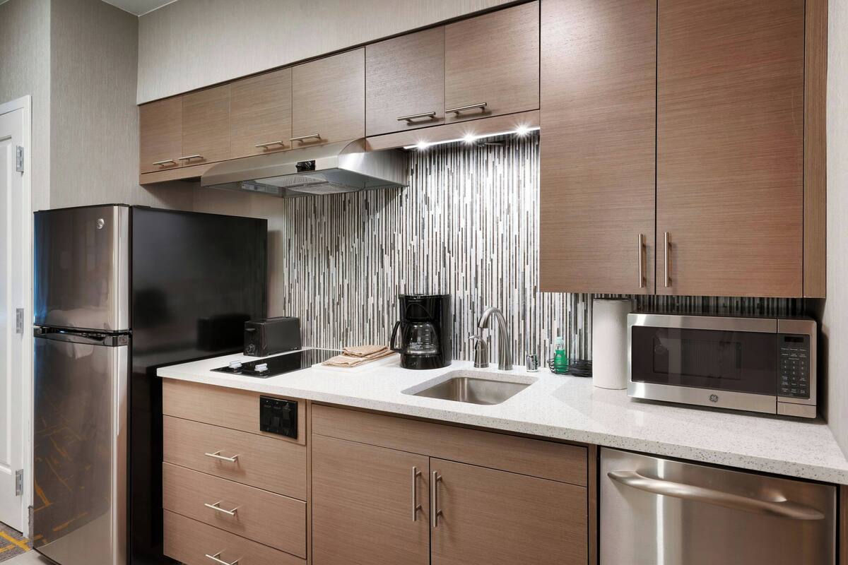 Una cocina moderna con electrodomésticos de acero inoxidable, armarios de madera y un salpicadero a rayas.
