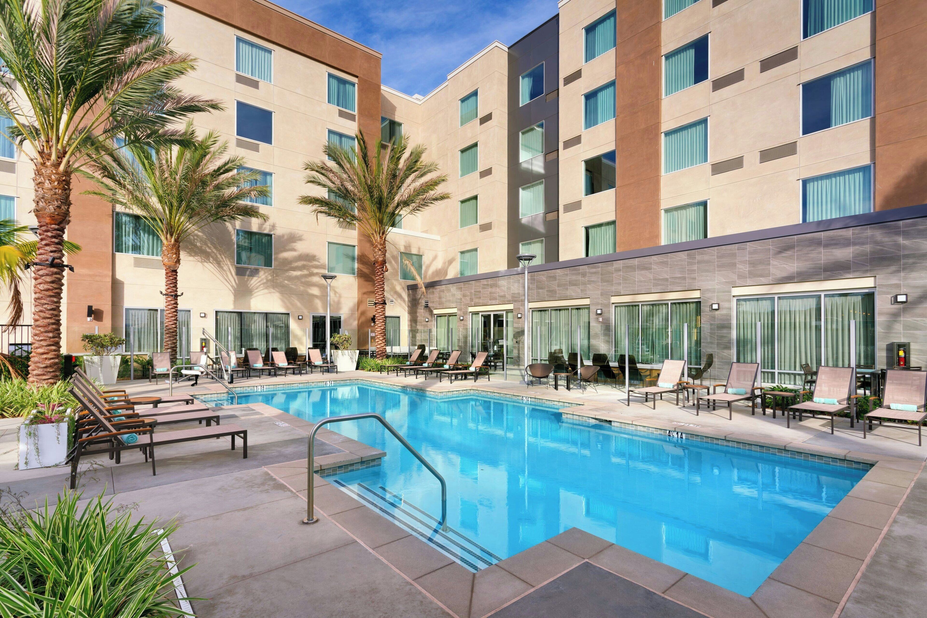 Una piscina al aire libre, sombrillas, sillones reclinables de piscina