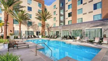 Una piscina al aire libre, sombrillas, sillones reclinables de piscina