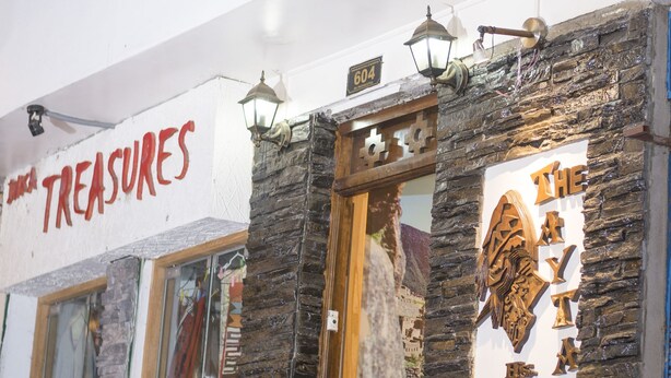 Un escaparate con un letrero que dice "TREASURES" y fachada de piedra.