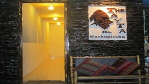 Entrada a un edificio con un cartel que dice "THE MACHIPEEHU" y un banco de madera afuera.