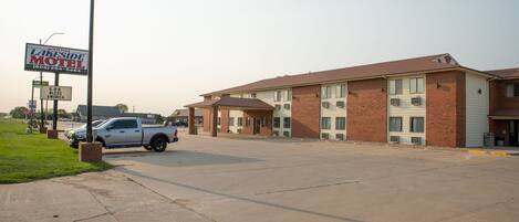 A motel with a brick facade, a parking lot, and a silver pickup truck parked in front.