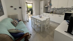 Une cuisine moderne avec des meubles blancs, un pare-feu en carreaux et un coin repas comprenant une table et des chaises blanches.
