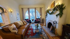A cozy living room with a leather sofa, a glass coffee table, and a fireplace. - Timeless Elegance ~ 1920's Sam Hughes Casita Mariposa ~ Walk to UA! Parking (Tucson)