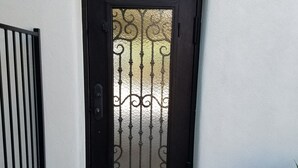 A black door with decorative glass panels, set in a stone-paved entrance area. - Timeless Elegance ~ 1920's Sam Hughes Casita Mariposa ~ Walk to UA! Parking (Tucson)
