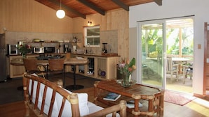 Una cocina con armarios de madera, un comedor con mesa y sillas, y un ventanal corredero que da a un patio exterior.
