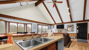 A spacious kitchen with a large island, wooden beams, and a ceiling fan.