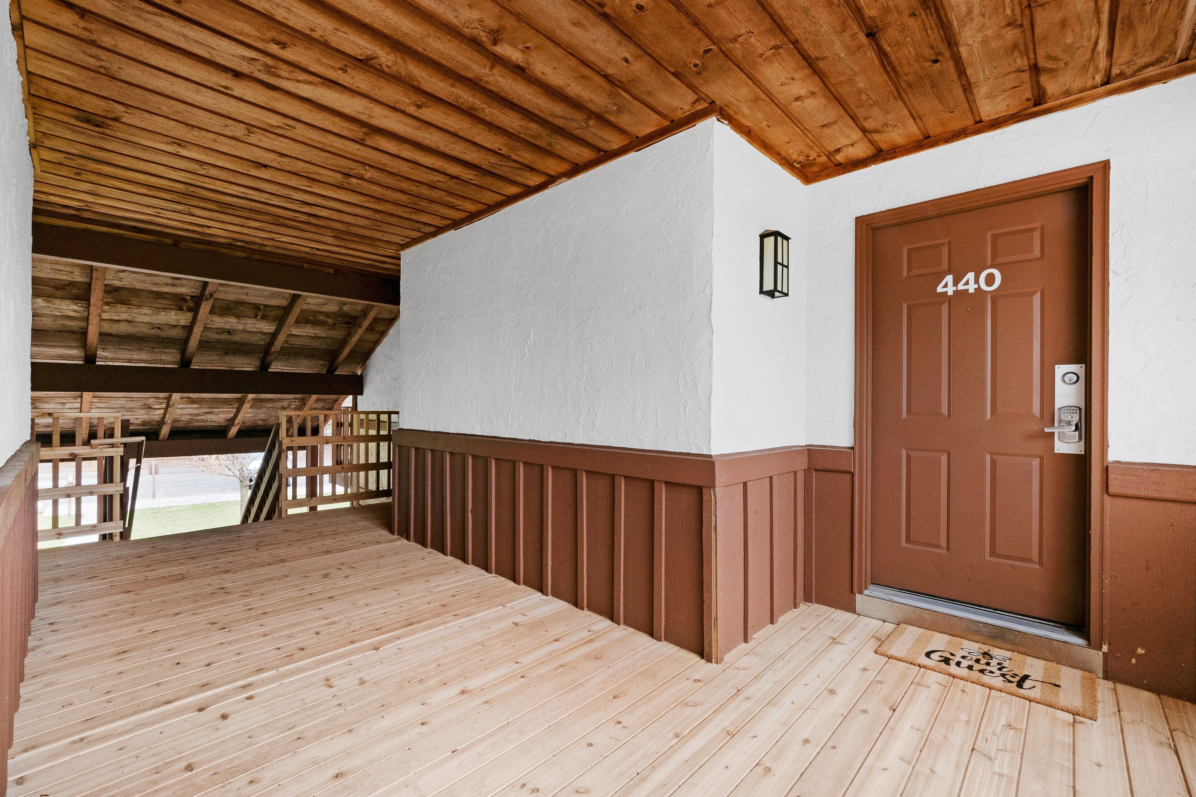Vestíbulo con suelo de madera, una puerta marrón con el número "440" y un felpudo.