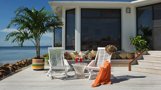 Eine Terrasse mit Liegestühlen, einem Blumentopf und einem Tisch mit Getränken.