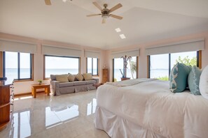 Ein Schlafzimmer mit einem großen Bett, einer Couch, einem Deckenventilator und Meerblick.