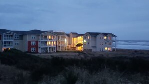 Un hôtel situé en bord de mer, avec plusieurs étages, des balcons et une entrée bien éclairée.