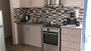 Cuina compacta amb forn integrat, fogó i microones. Hi ha armaris amb nassos, un mosaique a la paret i un rentaplat amb aixeta.