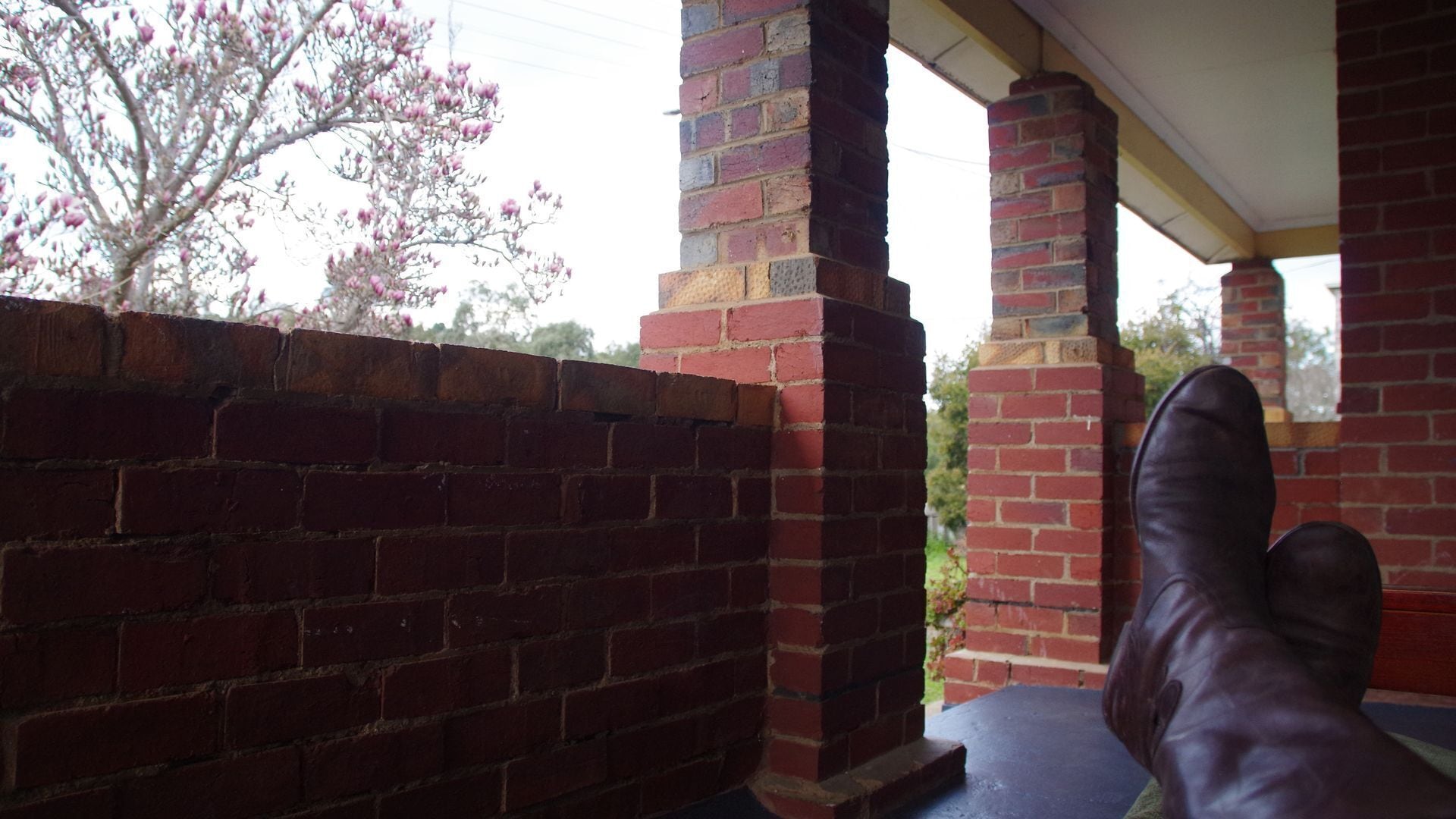 A brick wall and a porch with a person sitting.
