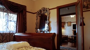 Una camera da letto con un letto di legno, un ampio specchio decorato e una finestra vista su alberi spogliati.