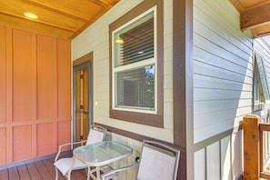 A covered porch with a table and two chairs, a wooden railing, and a window with blinds. - 'Bozeman Getaway' w/ Mountain Views, Near Downtown (Bozeman)