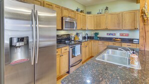 Una cocina moderna con electrodomésticos de acero inoxidable, gabinetes de madera, encimeras de granito y un lavamanos integrado.