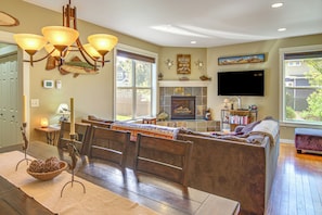 A spacious living room with a dining area, a fireplace, and a television mounted on the wall. - 'Bozeman Getaway' w/ Mountain Views, Near Downtown (Bozeman)