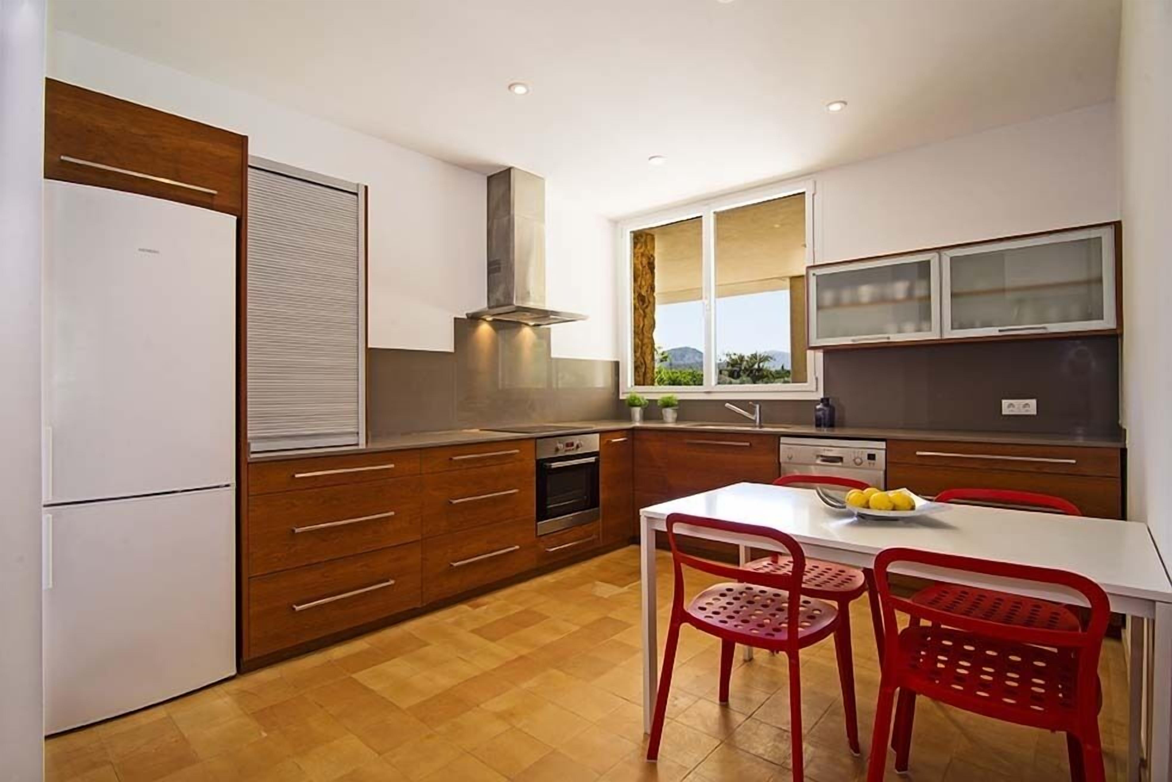 Een moderne keuken met houten kastjes, een roestvrijstalen afzuigkap en een raam met uitzicht.