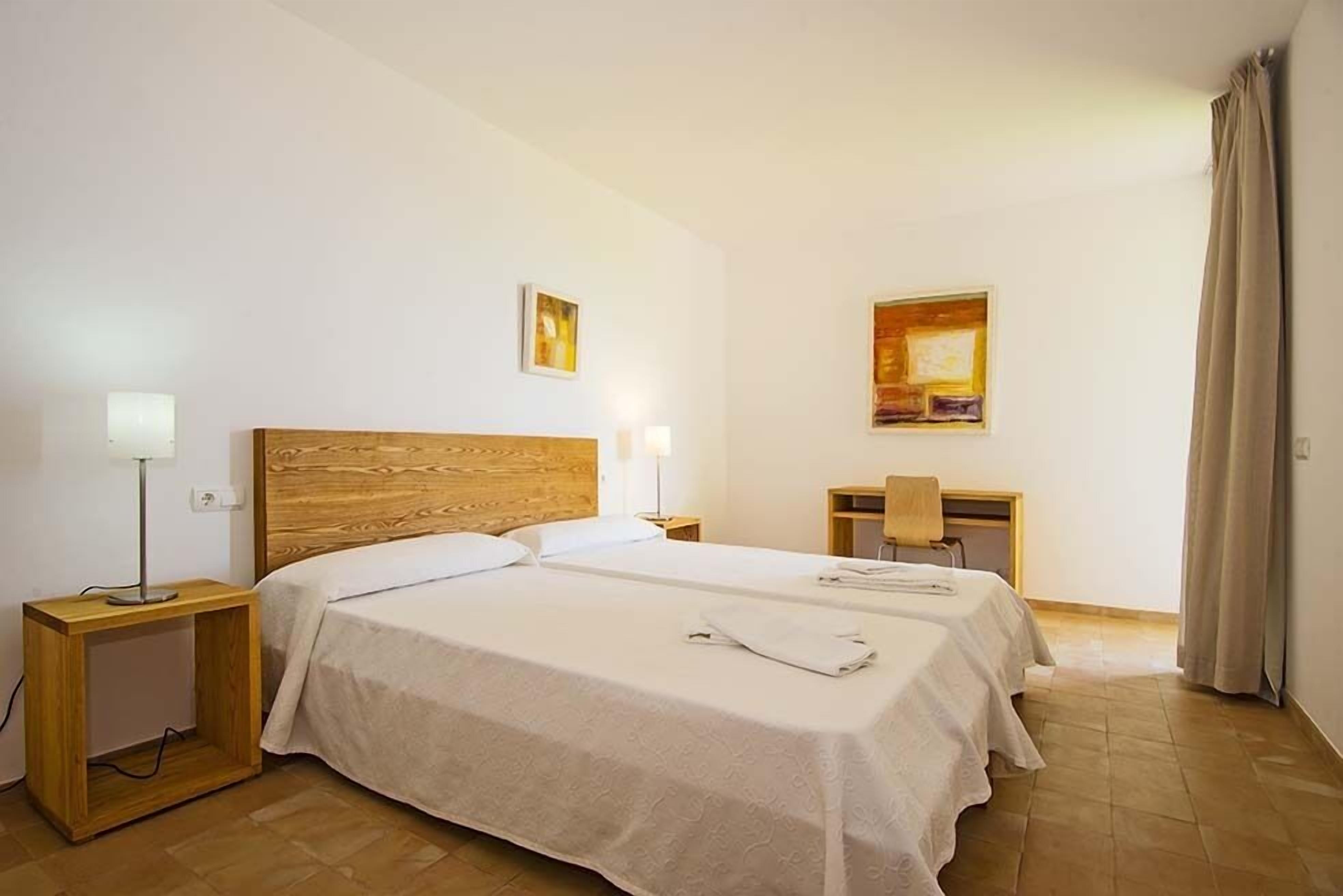 Une chambre d’hôtel avec deux lits, un bureau et deux tables de chevet avec des lampes.