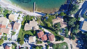 An aerial view of a coastal residential area with houses, a beach, and clear waters. - Angelina: Charming studio, terrace views, steps from Kalami beach (Kalami)