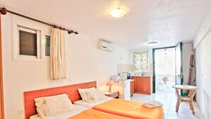 A hotel room with two beds, a kitchenette, a bathroom, and a balcony. - Angelina: Charming studio, terrace views, steps from Kalami beach (Kalami)