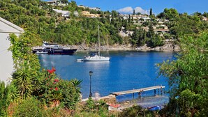 A coastal marina with boats, a dock, and residential buildings on a hillside. - Angelina: Charming studio, terrace views, steps from Kalami beach (Kalami)