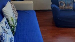 A room with a blue sofa, a smaller blue armchair, and a wooden floor. - Villa lardarina (Corniglia Liguria)