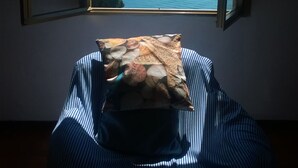 A room with a bed, a window with a view of a coastline, and a pillow with a seashell pattern. - Villa lardarina (Corniglia Liguria)