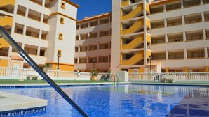 A hotel with multiple balconies, a swimming pool, and a white and yellow exterior.