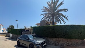 Ein silbernes Auto parkt auf einer Auffahrt mit einer Steinsäule und einem gepflegten Heckenstreifen.