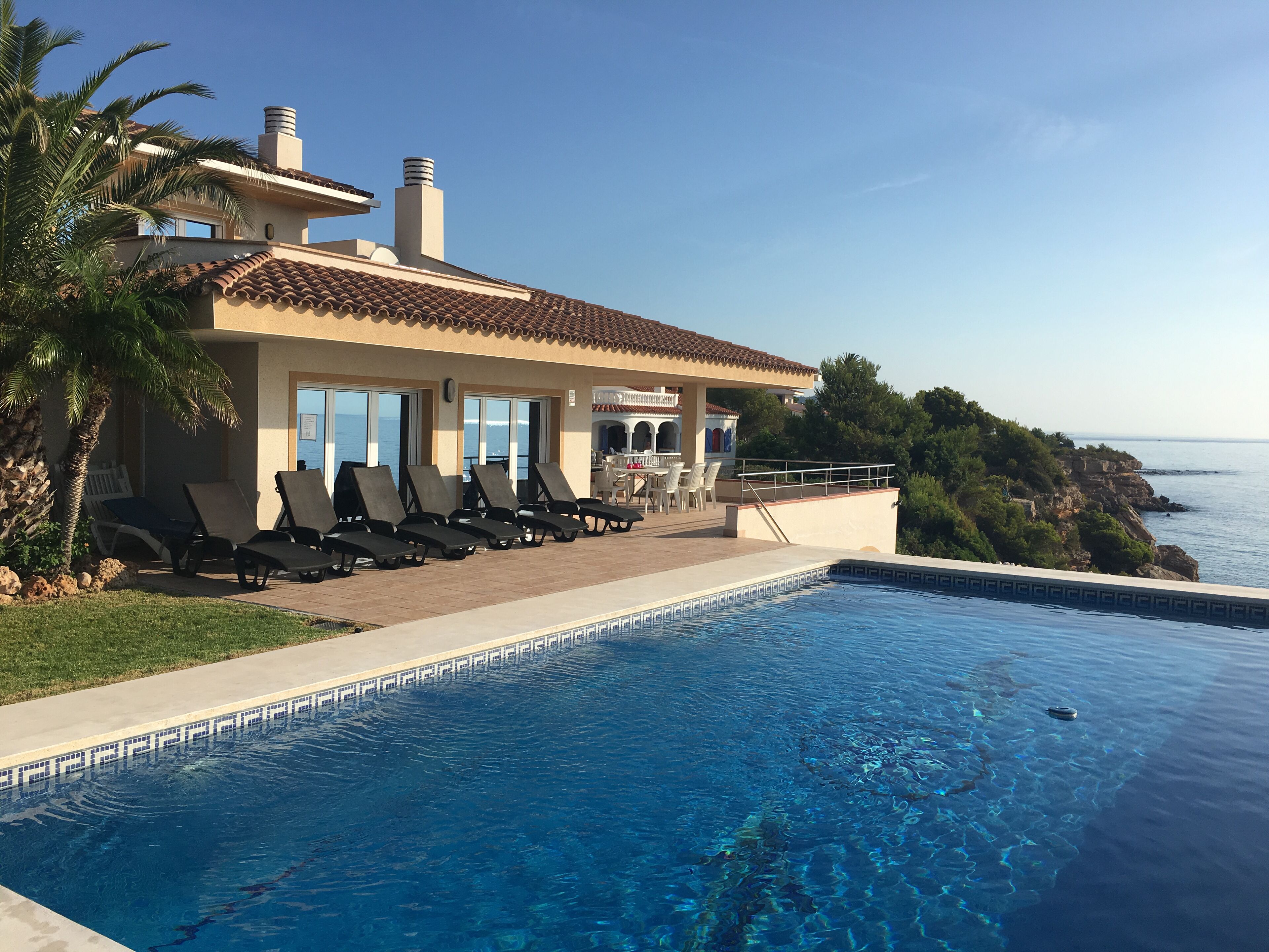 Zona de piscina con sillones de descanso y vista al océano.