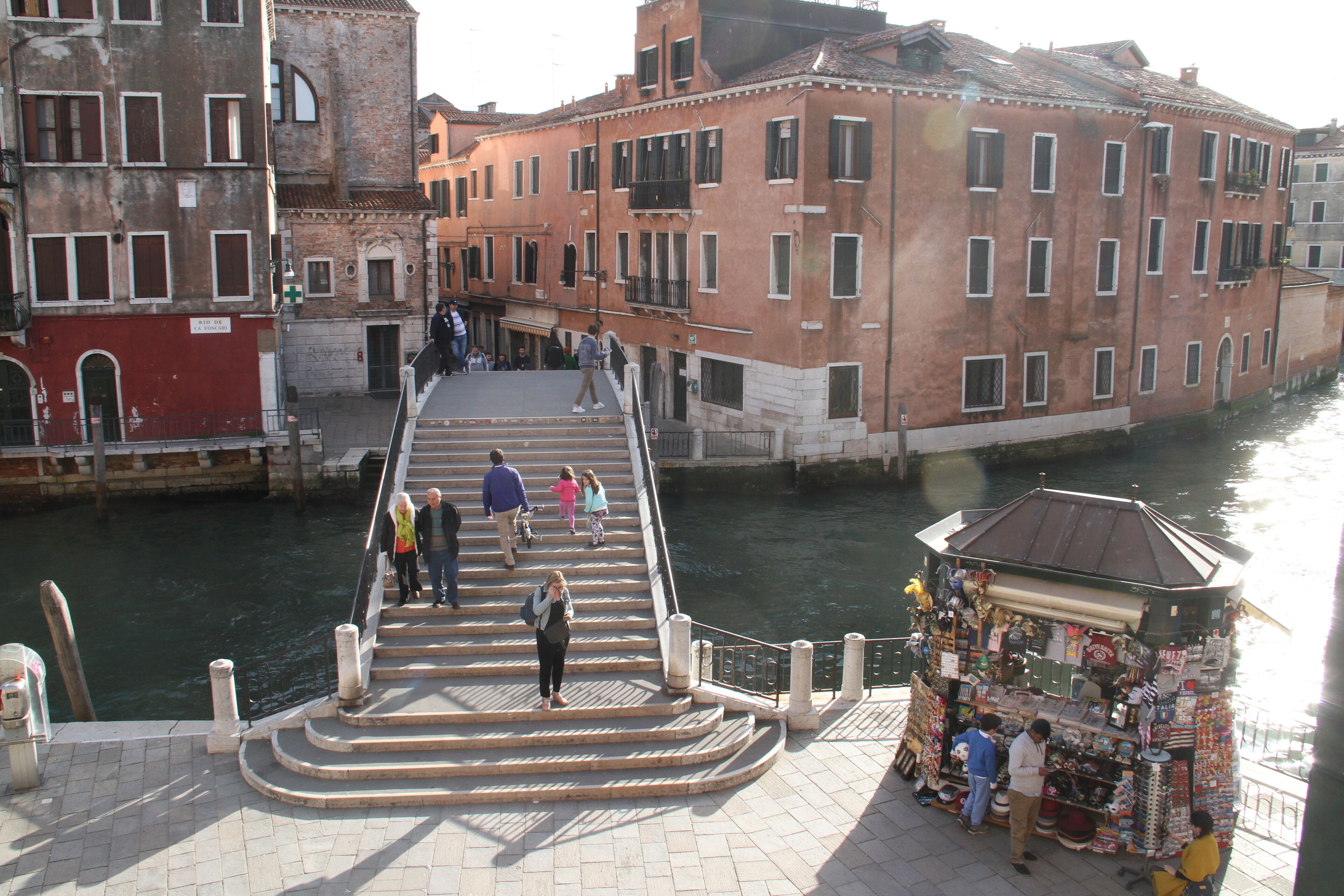 Un puente peatonal con escaleras que conducen a un canal, rodeado de edificios históricos.