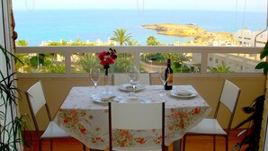 A dining table with a floral tablecloth, wine glasses, and a bottle on a balcony overlooking the sea. - Apartment/ flat - El Campello (El Campello)