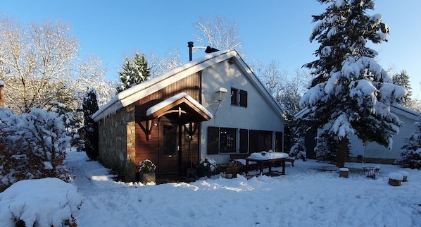 A wooden cabin with a sloped roof, a stone foundation, and a wooden porch.