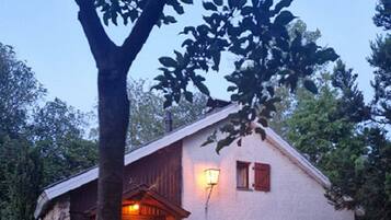 A rustic house with a stone exterior, a wooden door, and a patio with outdoor furniture.