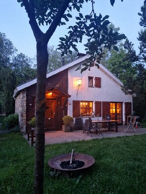 A rustic house with a stone exterior, a wooden door, and a patio with outdoor furniture.