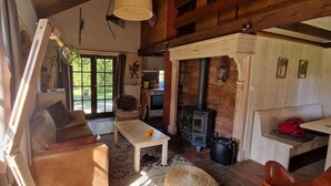 A cozy living room with a sofa, a wooden table, a fireplace, and a view of the outdoors.