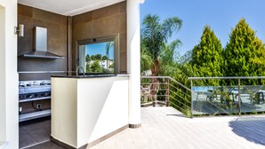 Een moderne keuken met een ingebouwde kookplaat en een raam met uitzicht op een balkon met een glazen balustrade.