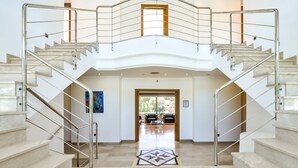 Een ruim, modern interieur met een centrale trap, geflankeerd door twee sets trappen naar een hoger niveau.